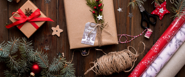 Flera julklappar inslagna i brunt papper med vackra dekorationer såsom torkad apelsin och grankvistar.