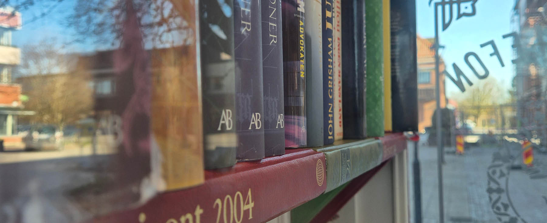 Ett hyllplan med böcker i bibliokiosken. Hyllplanet är gjort av gamla uppslagsverk.