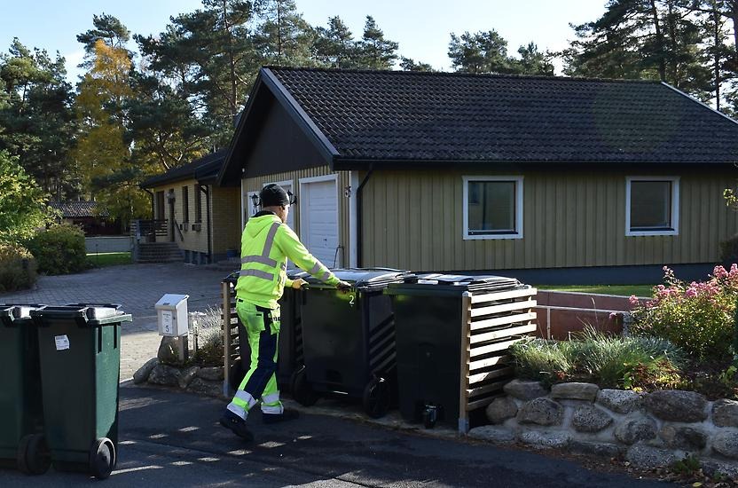 En person i varselkläder ställer ut två fyrfackskärl.