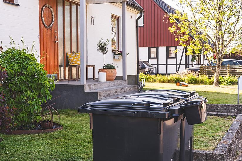 Två gråa avfallskärl utanför en villa.