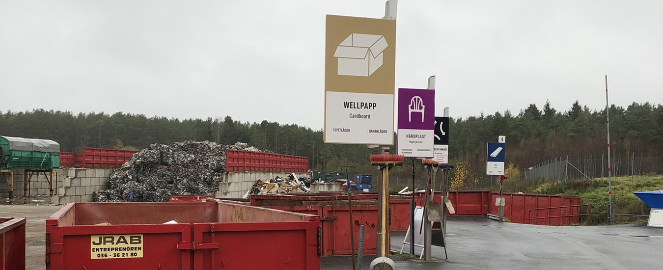 Översiktsbild över en återvinningscentral med röda containrar på rad.