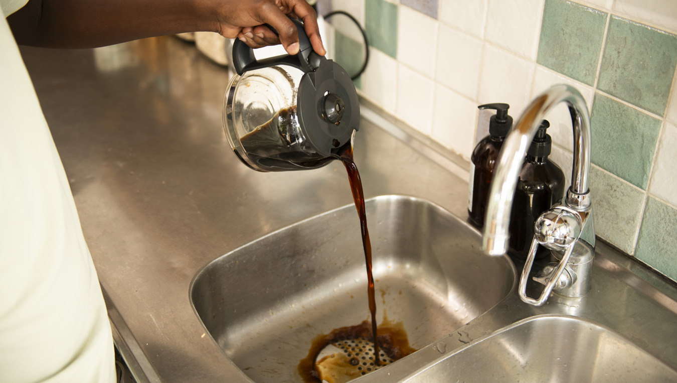 En person häller kaffe i vasken.