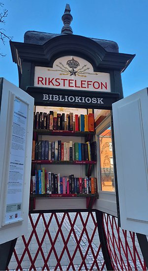 Bibliokiosken med öppna dörrar. Inuti syns tre hyllplan med böcker.