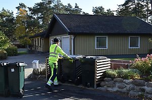 En person i varselkläder ställer ut två fyrfackskärl.