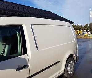 Vit företagsbil på en återvinningscentral.