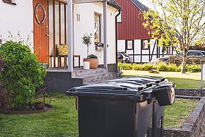 Två gråa avfallskärl utanför en villa.